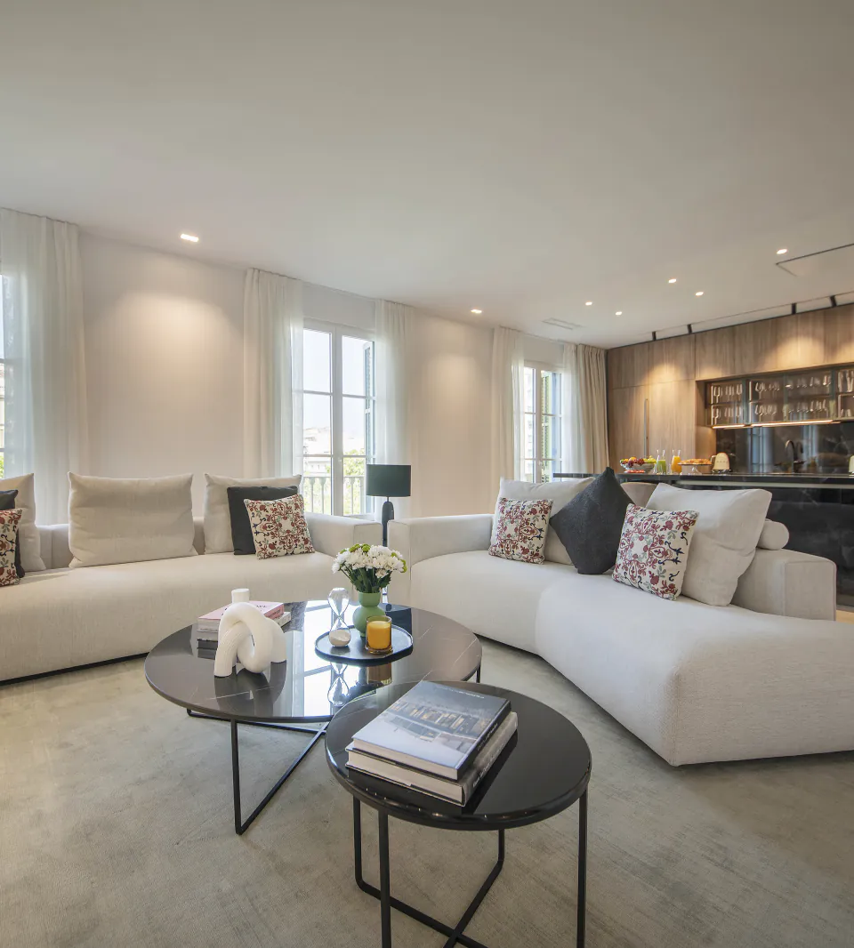 Suite Prestige living room with pale sofas, tall windows and an open kitchen