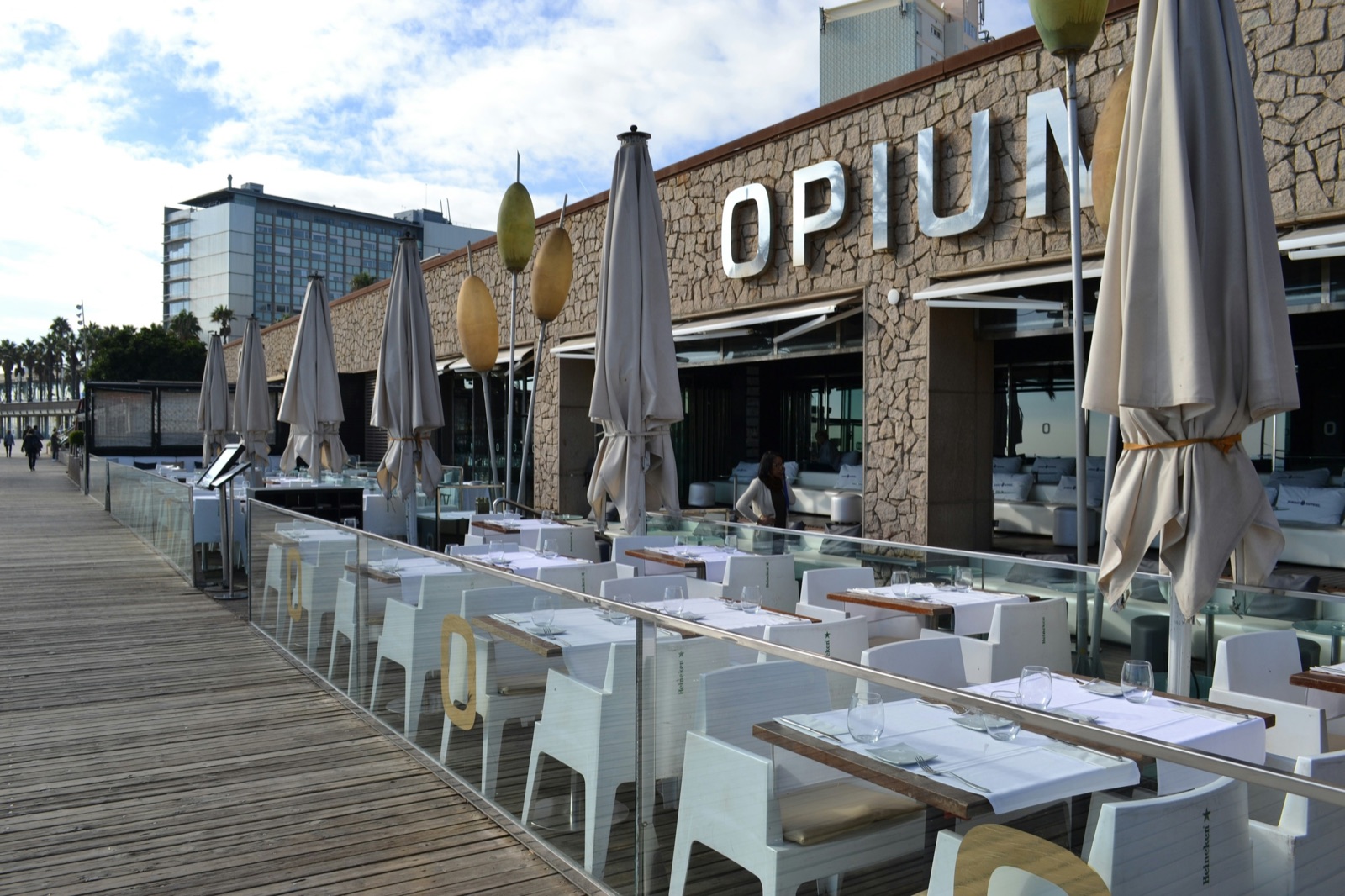 Restaurant terrace tables arranged beneath umbrellas beside Barcelona's waterfront