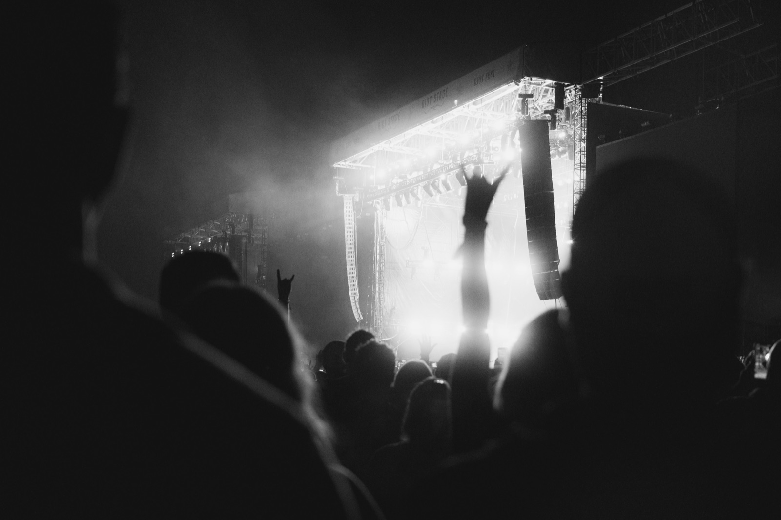 A concert crowd silhouetted against a brightly lit live music stage