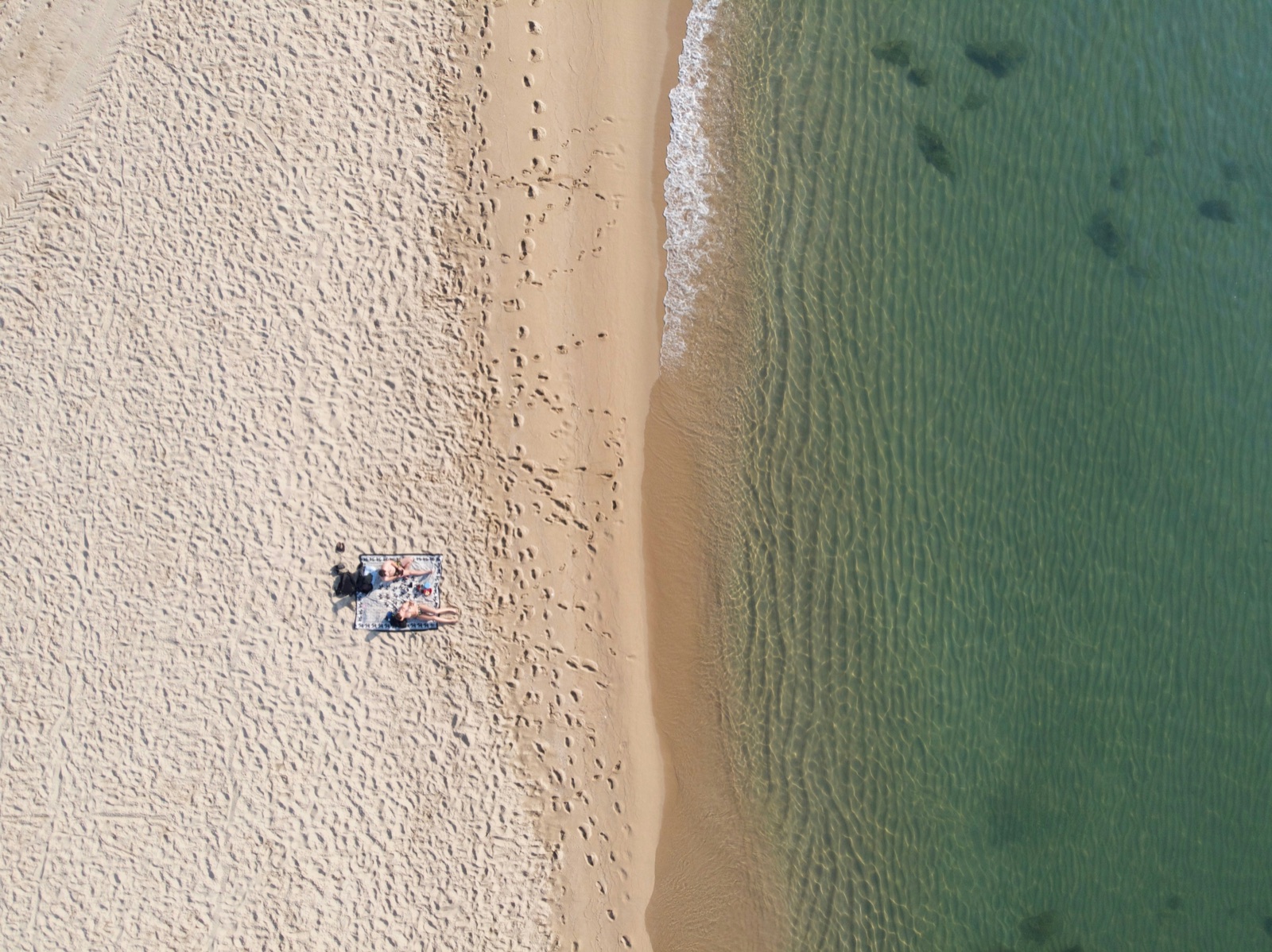 An early aerial view of pale sand and clear water at Bogatell beach in Barcelona