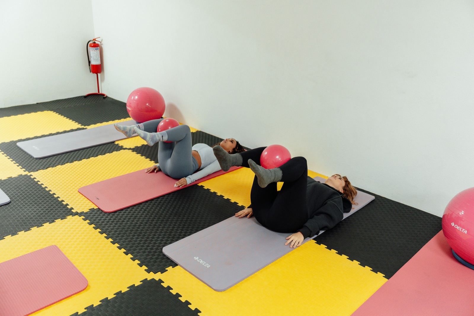 Two people practising Pilates with exercise balls in a bright studio