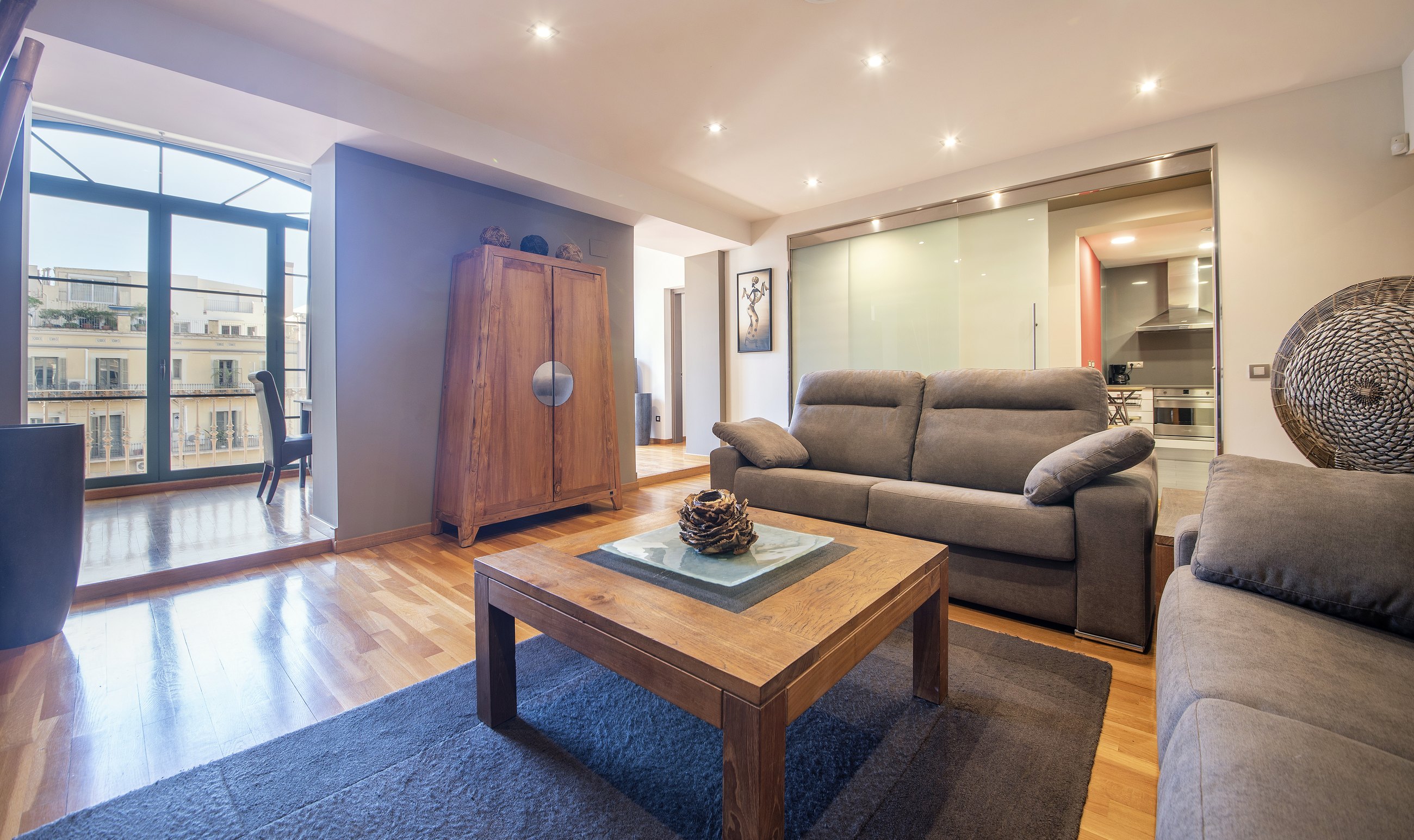 Suite Sol&eacute;a living room with open kitchen and balcony windows in Barcelona
